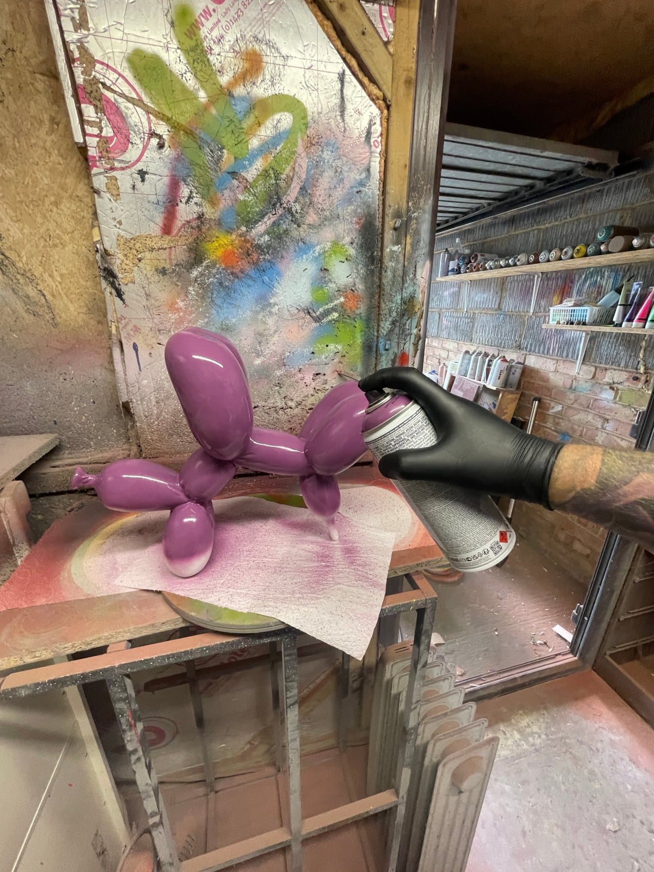 A purple balloon dog being spray-painted in the workshop